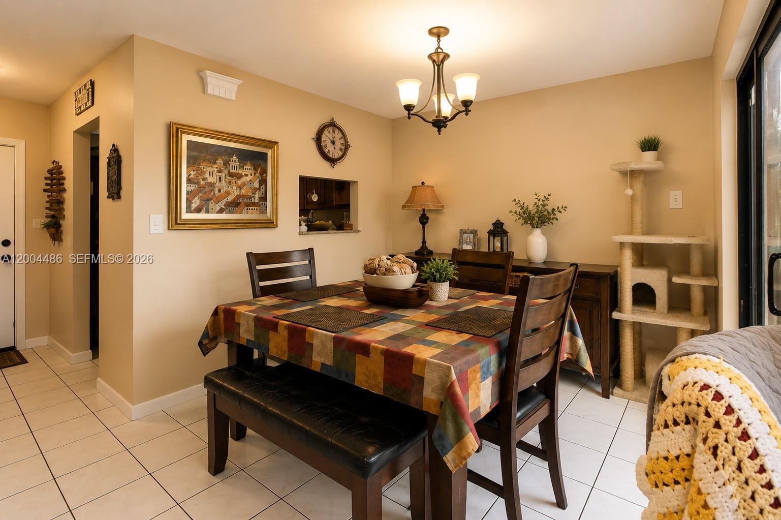 A dining room features a checkered tablecloth, wooden chairs, a bench, and a cat tree — 15071 SW 127th Ct, Miami FL 33186, MIAMI, FL