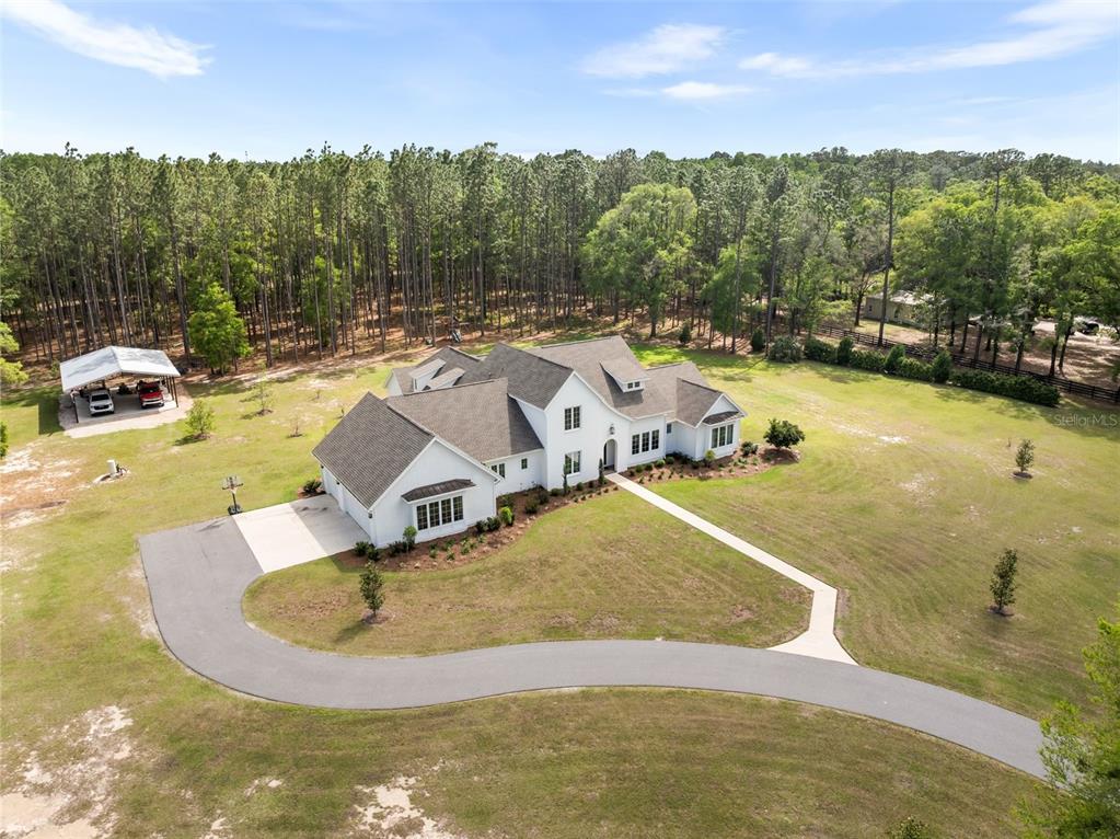 An aerial view shows a white house with a gray roof, driveway, and detached carport — 14503 NW 50TH PLACE, ALACHUA, FL