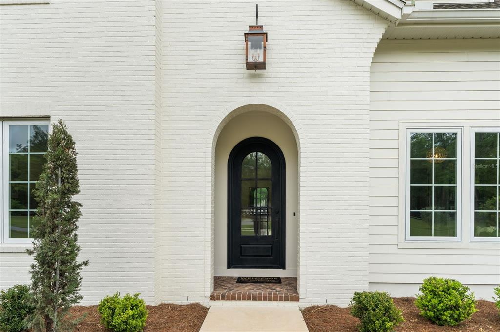 A white brick exterior features an arched black front door and a hanging lantern light — 14503 NW 50TH PLACE, ALACHUA, FL