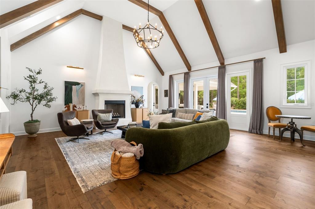A living room with a vaulted ceiling, exposed wood beams, fireplace, and hardwood floors — 14503 NW 50TH PLACE, ALACHUA, FL