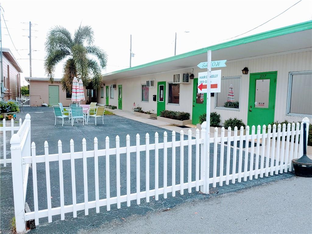 A white picket fence encloses a paved courtyard with outdoor seating in front of a building — 215 N SCENIC HIGHWAY, FROSTPROOF, FL