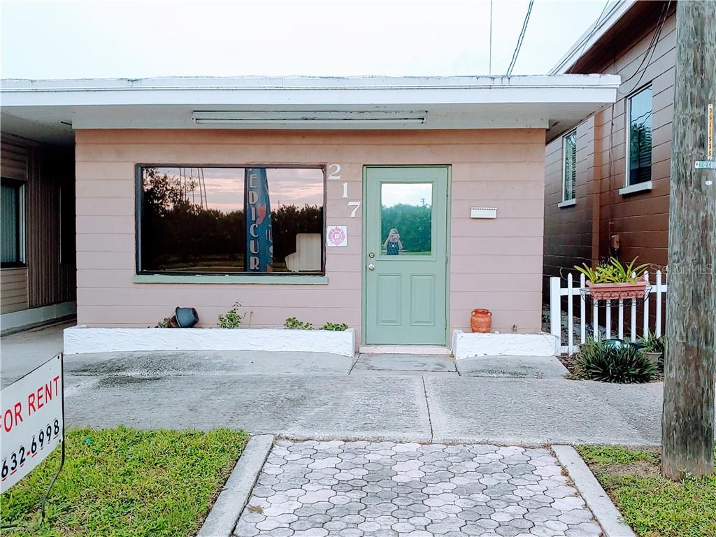 A single-story commercial building with a light pink exterior, a green door, and a large window — 215 N SCENIC HIGHWAY, FROSTPROOF, FL