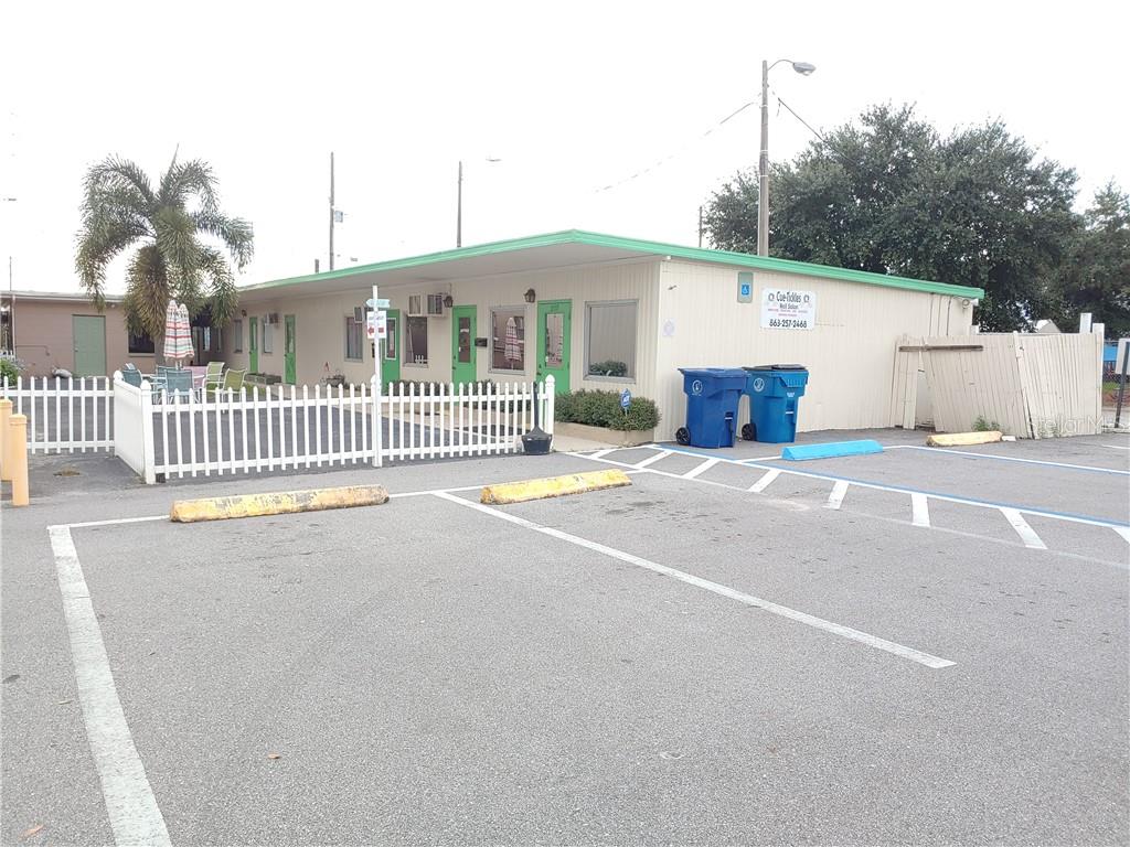 A single-story commercial building with a parking lot and white picket fence in front — 215 N SCENIC HIGHWAY, FROSTPROOF, FL