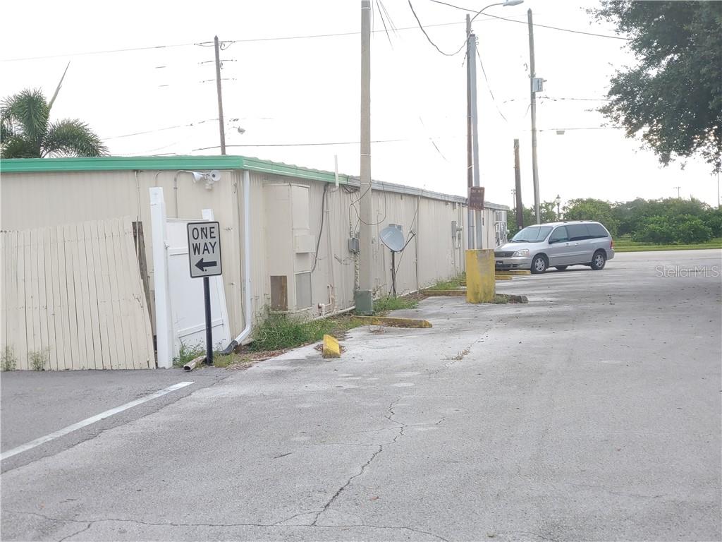 A one-way sign stands next to a beige building with a parking lot — 215 N SCENIC HIGHWAY, FROSTPROOF, FL