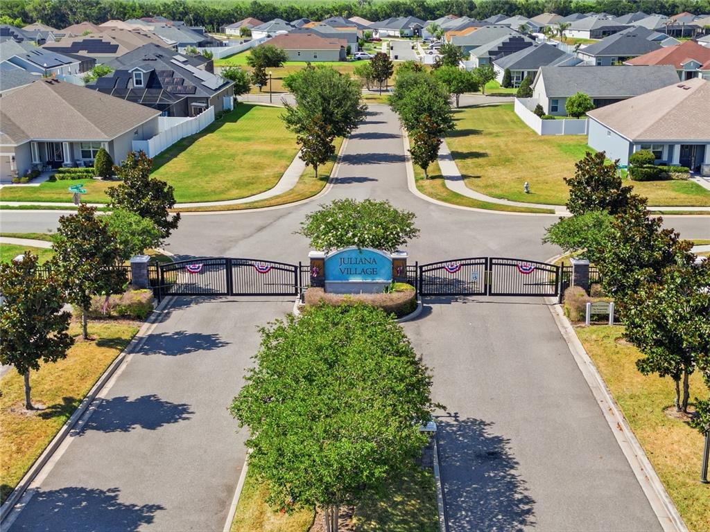 An aerial view shows the gated entrance to a residential neighborhood named Juliana Village — 319 TRAVELERS CREEK DRIVE, AUBURNDALE, FL