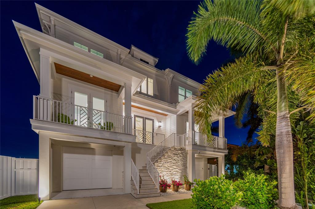 A two-story white house with a garage, elevated porch, and exterior stone accents at night — 17715 WALL CIRCLE, REDINGTON SHORES, FL