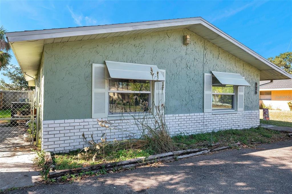 A single-story house with light green stucco walls, white brick accents, and two windows — 926 LAKE PALMS DRIVE, LARGO, FL