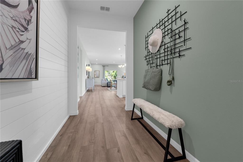 A hallway features wood-look flooring, a shiplap wall, and a bench against a green wall — 23595 GRINDSTONE WAY, SORRENTO, FL