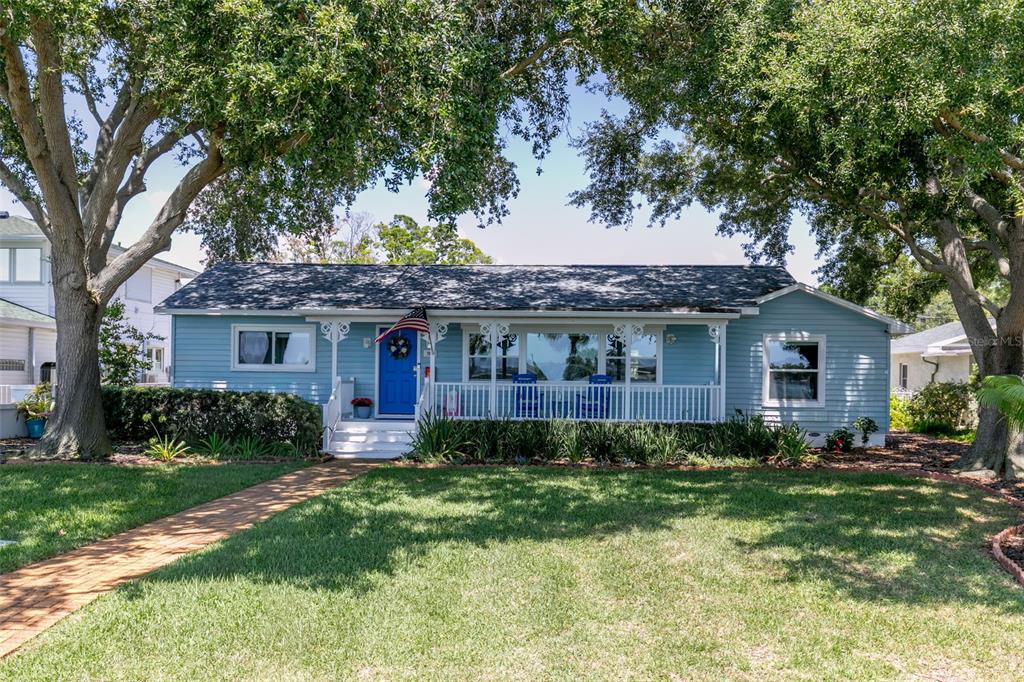 A light blue single-story house with a front porch and large shade trees — 110 SUNSET DRIVE S, ST PETERSBURG, FL