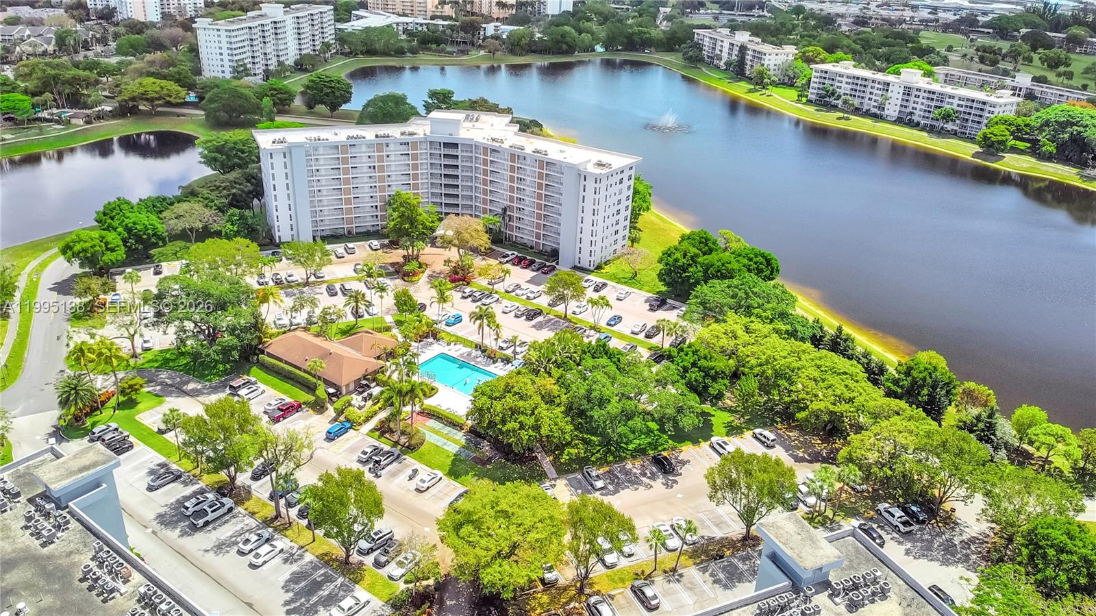 An aerial view shows a large apartment complex with a pool and parking lot — 3010 N Course Dr # 104, Pompano Beach FL 33069, POMPANO BEACH, FL