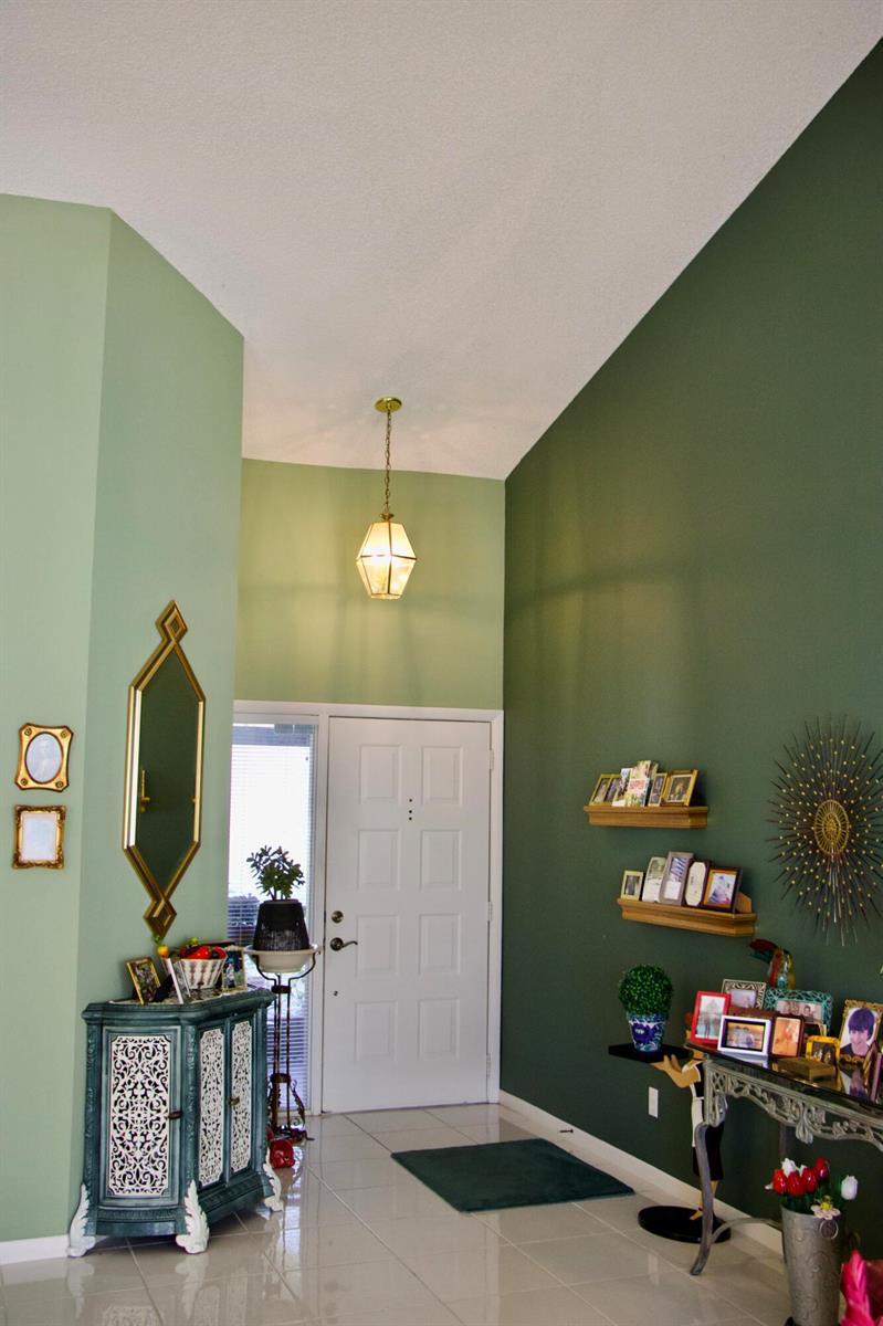 An entryway features two-tone green walls, a white front door, tiled floors, and decorative accents — 8304 Waterline Drive # 103, Boynton Beach FL 33472, BOYNTON BEACH, FL