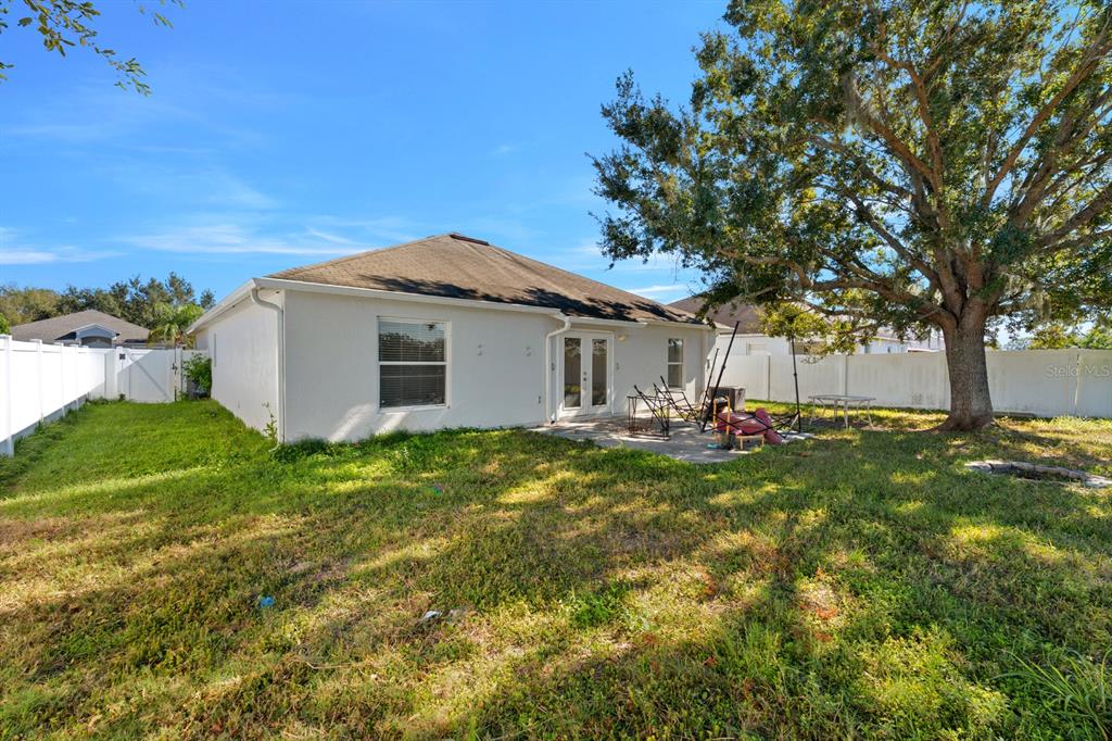 The exterior view shows the back of a house with a patio and large tree — 3609 TRAPNELL GROVE LOOP, PLANT CITY, FL