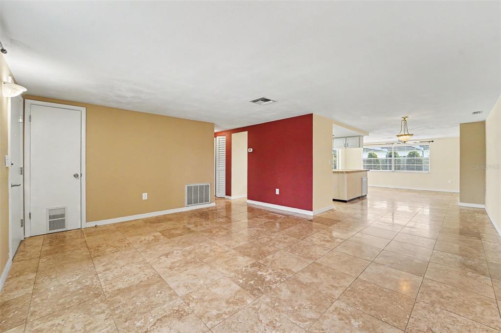 An open-concept living area features tan tile flooring, a red accent wall, and beige walls — 4316 CHIPMUNK DRIVE, NEW PORT RICHEY, FL
