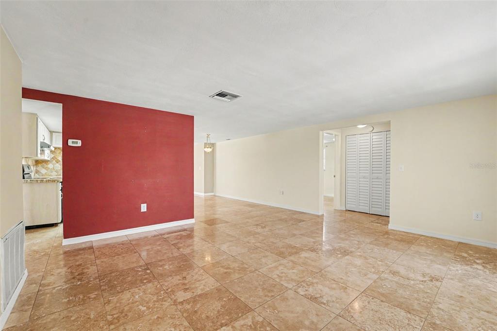 A spacious room with beige tile flooring, a red accent wall, and white walls — 4316 CHIPMUNK DRIVE, NEW PORT RICHEY, FL