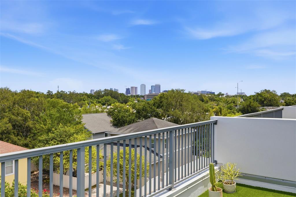 A balcony with a metal railing overlooks a suburban neighborhood and a distant city skyline — 2442 W MISSISSIPPI AVENUE UNIT 1, TAMPA, FL