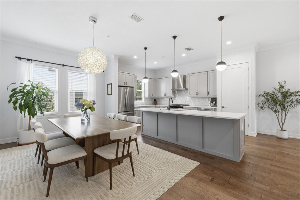 A bright kitchen and dining area features a wooden table, gray island, and pendant lighting — 2442 W MISSISSIPPI AVENUE UNIT 1, TAMPA, FL