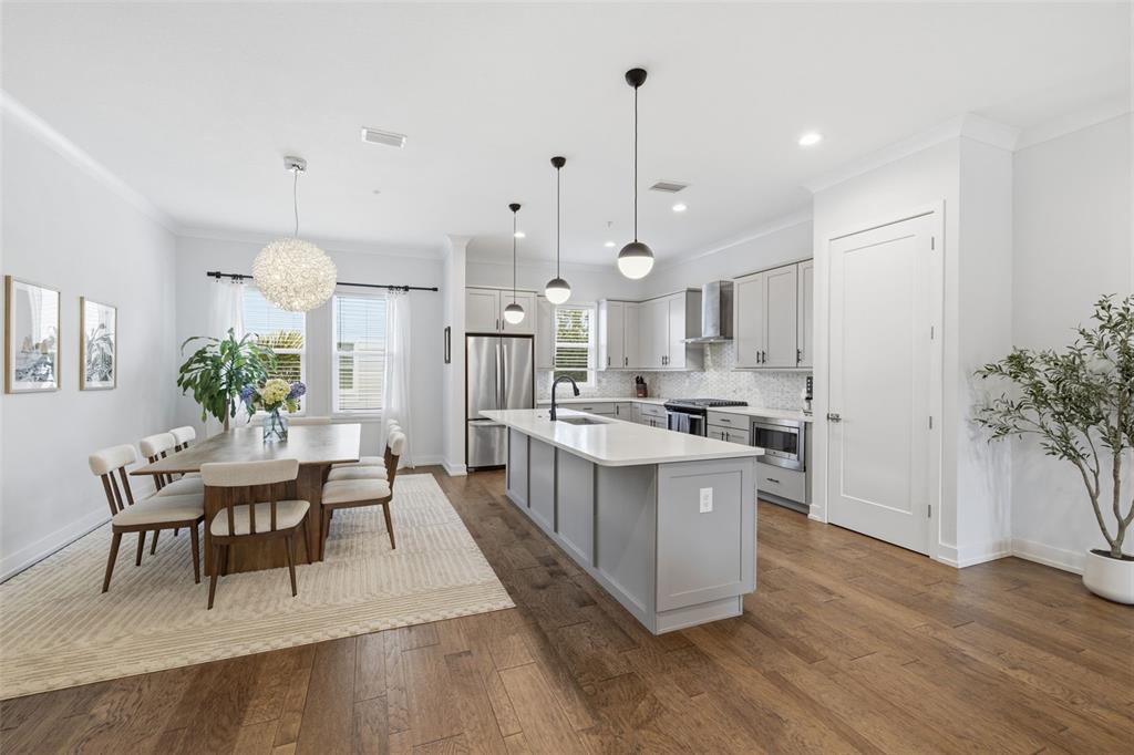 A modern kitchen and dining area features gray cabinetry, a central island, and hardwood floors — 2442 W MISSISSIPPI AVENUE UNIT 1, TAMPA, FL