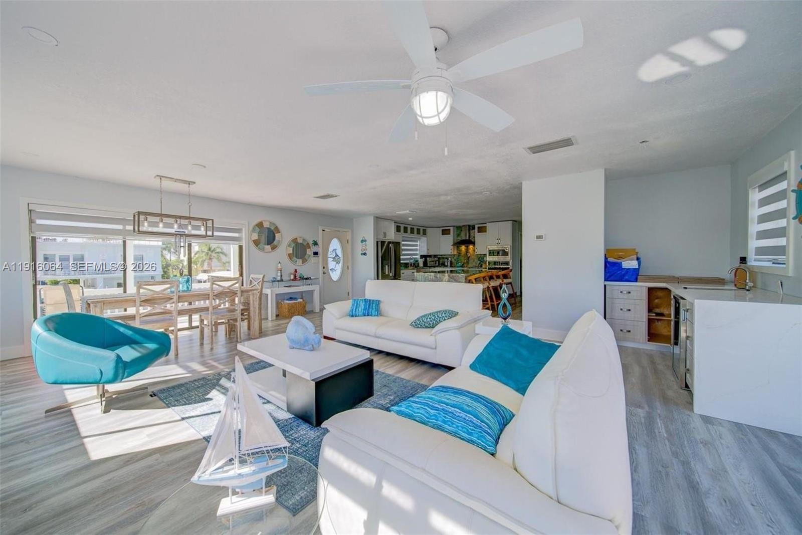 A bright open-concept living and dining area features white sofas, blue accents, and light flooring — 2 Snipe Rd, Key Largo FL 33037, KEY LARGO, FL