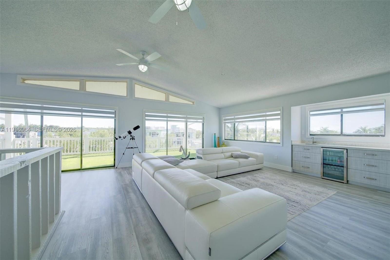 A bright living room features white leather sectionals, light wood flooring, and a wet bar — 2 Snipe Rd, Key Largo FL 33037, KEY LARGO, FL