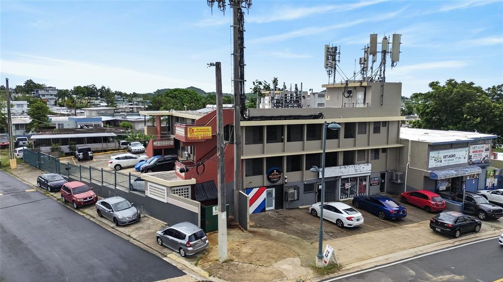 An exterior view of a multi-story commercial building with a parking lot and cell towers — 1 HNAS DAVILA, BETANCES ESQ A D, BAYAMON, PR