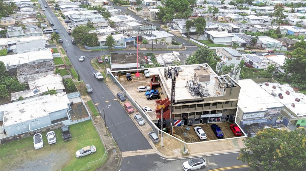 An aerial view shows a multi-story commercial building with a parking lot and cell tower — 1 HNAS DAVILA, BETANCES ESQ A D, BAYAMON, PR
