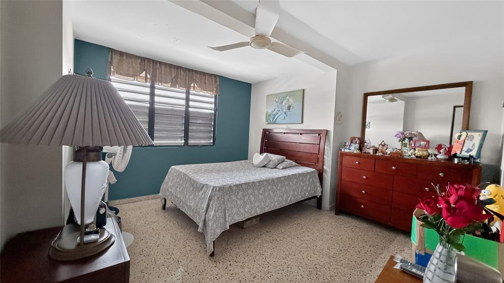 A bedroom features a bed, a wooden dresser with a mirror, and a teal accent wall — 1 HNAS DAVILA, BETANCES ESQ A D, BAYAMON, PR