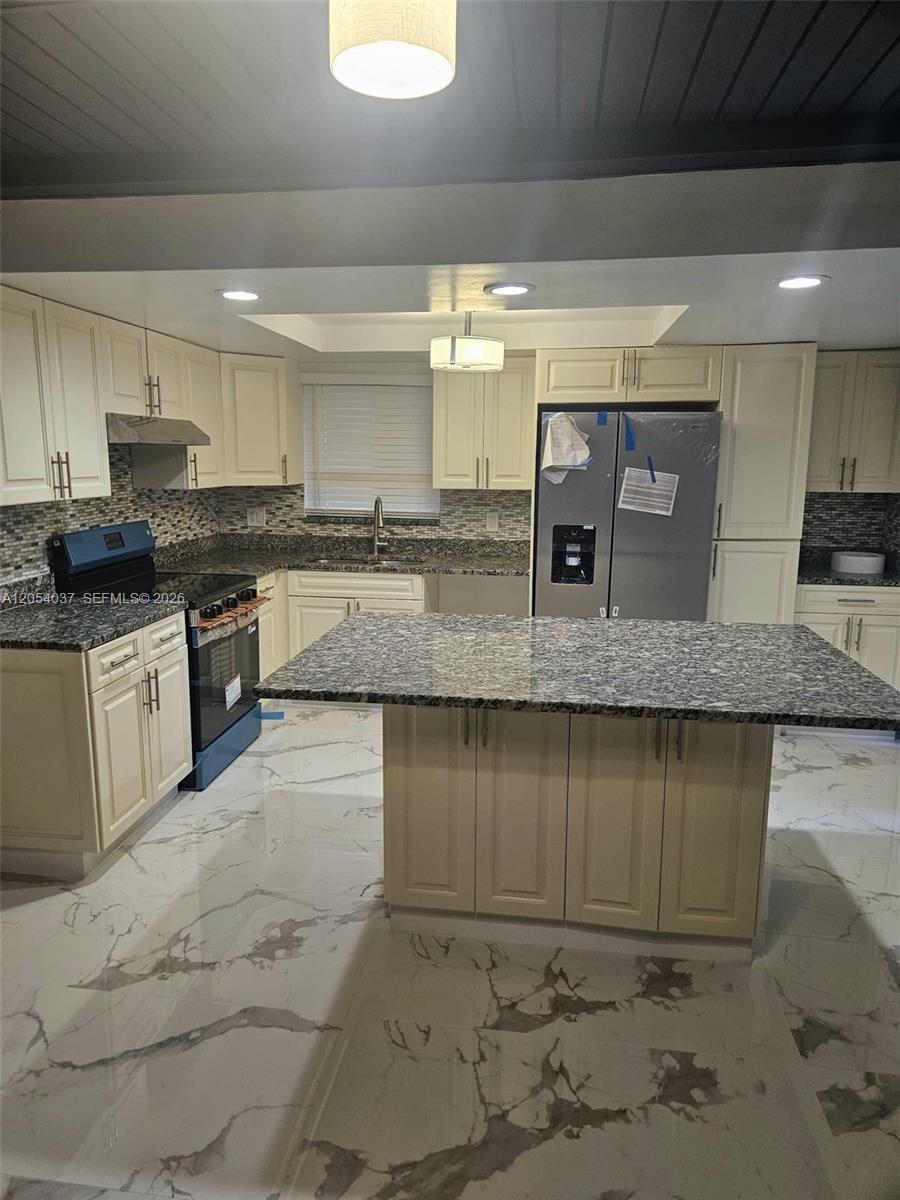 A kitchen features cream cabinets, granite countertops, and white marble-patterned tile flooring — 2950 Kirk Rd # 2950, Lake Worth FL 33461, LAKE WORTH, FL