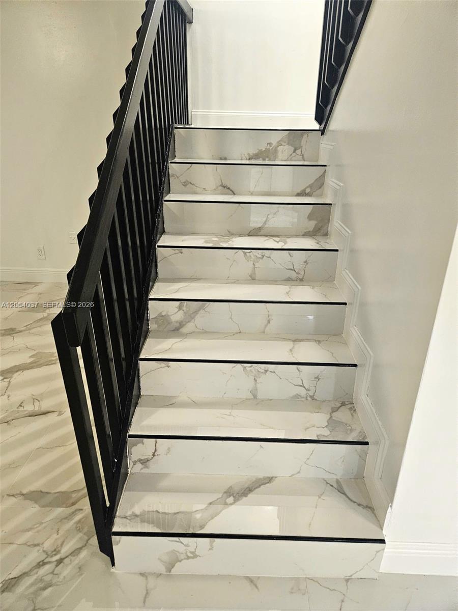 A staircase features white marble-look tile steps with black trim and a black metal railing — 2950 Kirk Rd # 2950, Lake Worth FL 33461, LAKE WORTH, FL