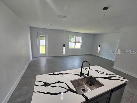 A kitchen island with a marble-patterned countertop and sink overlooks an open-concept living area — 0 ROBINSON DRIVE, HAINES CITY, FL