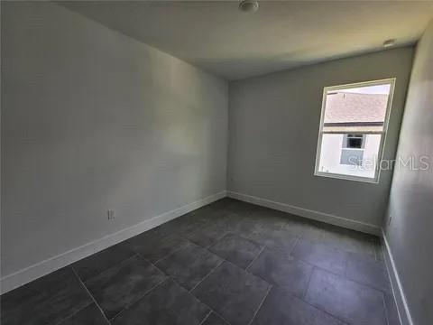An empty bedroom features light gray walls, white baseboards, and large dark gray floor tiles — 0 ROBINSON DRIVE, HAINES CITY, FL