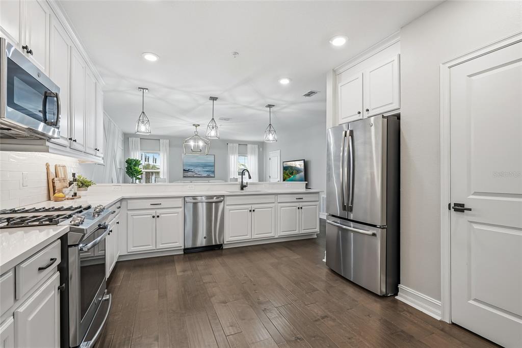 A modern kitchen features white cabinets, stainless steel appliances, and dark wood flooring — 5120 BRIDGE STREET UNIT 5, TAMPA, FL