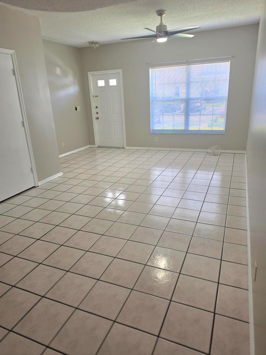 An empty room with light-colored tile flooring, a ceiling fan, and a front entrance door — 51 Whitehead Circle # 51, Weston FL 33326, WESTON, FL