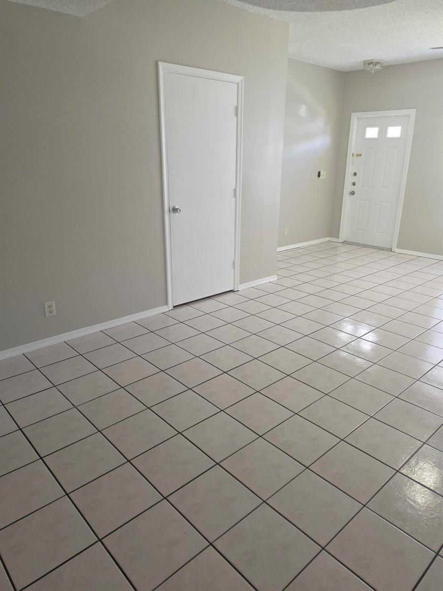 An interior view of a room with light-colored tile flooring, white trim, and a white door — 51 Whitehead Circle # 51, Weston FL 33326, WESTON, FL