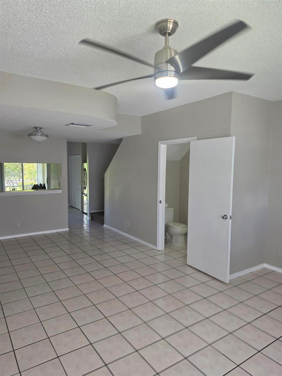 A room with light-colored tile flooring, gray walls, a ceiling fan, and an open bathroom — 51 Whitehead Circle # 51, Weston FL 33326, WESTON, FL