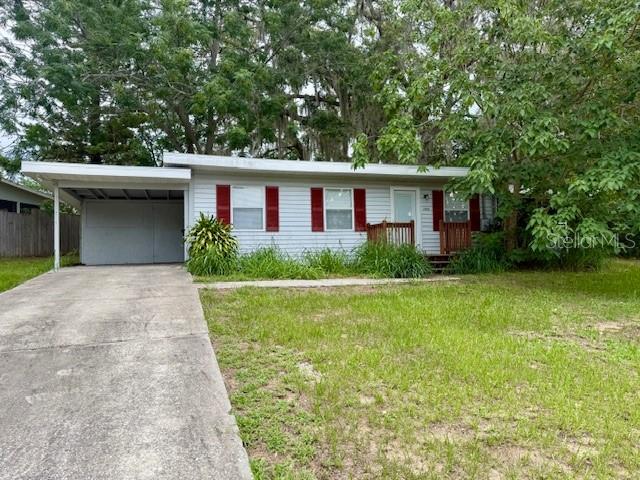 A single-story house with light gray siding, red shutters, and an attached carport — 31538 ANDERSON DRIVE, TAVARES, FL