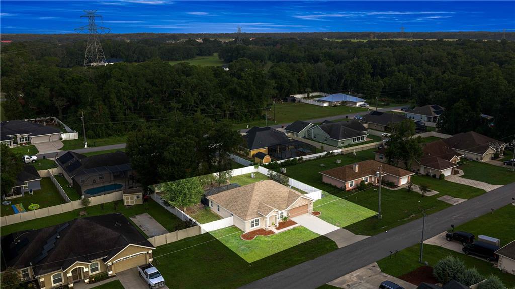 An aerial view shows a single-story suburban house with a tan roof and fenced backyard — 16376 SE 81ST COURT, SUMMERFIELD, FL