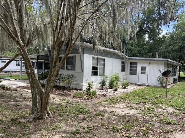 A white mobile home with a screened porch sits among trees draped in Spanish moss — 16716 SE 101ST COURT ROAD, SUMMERFIELD, FL