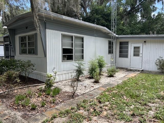 A single-story mobile home with white vertical siding and a gray roof sits outdoors — 16716 SE 101ST COURT ROAD, SUMMERFIELD, FL