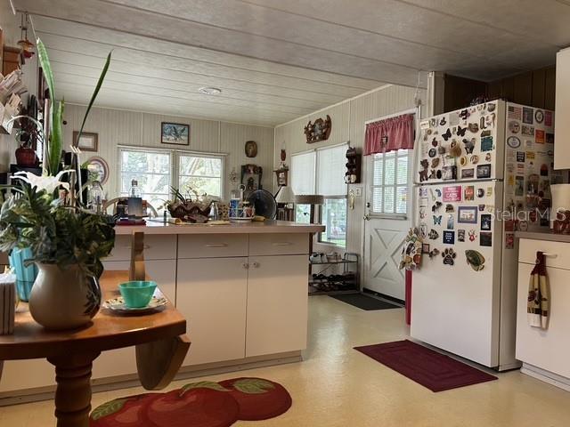A kitchen features white cabinets, a central island, and a refrigerator covered in magnets — 16716 SE 101ST COURT ROAD, SUMMERFIELD, FL