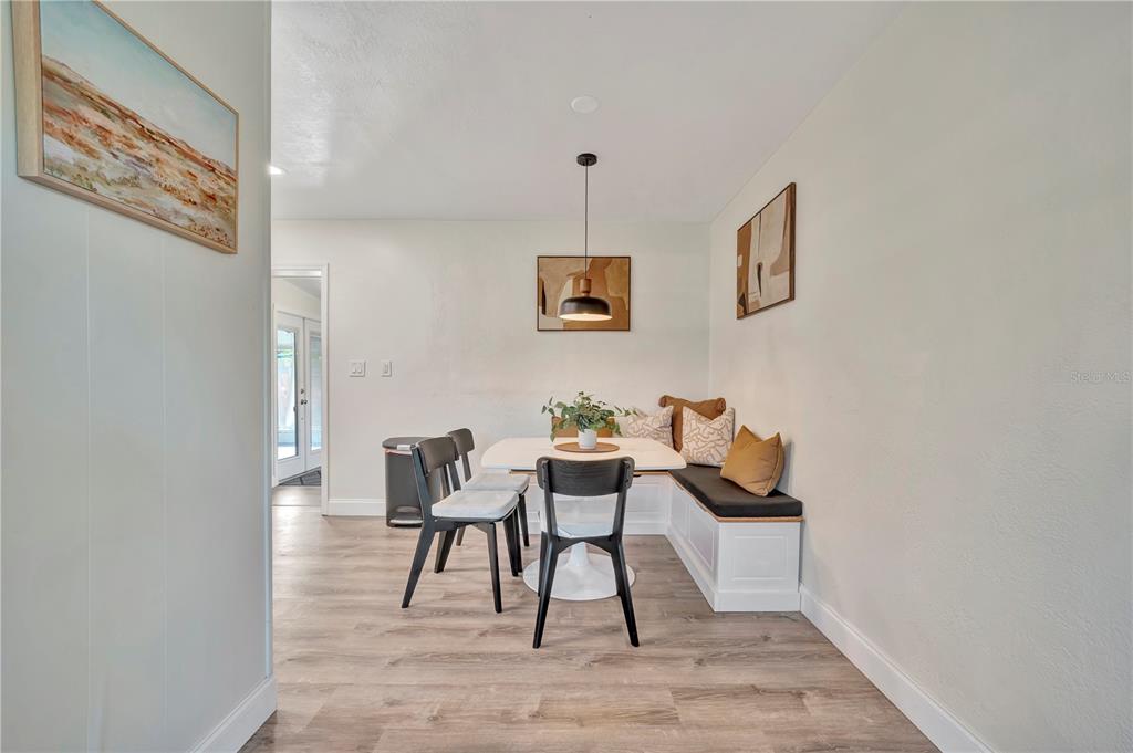 A dining area features a white table, black chairs, and a built-in corner bench seat — 4002 W OKLAHOMA AVENUE, TAMPA, FL