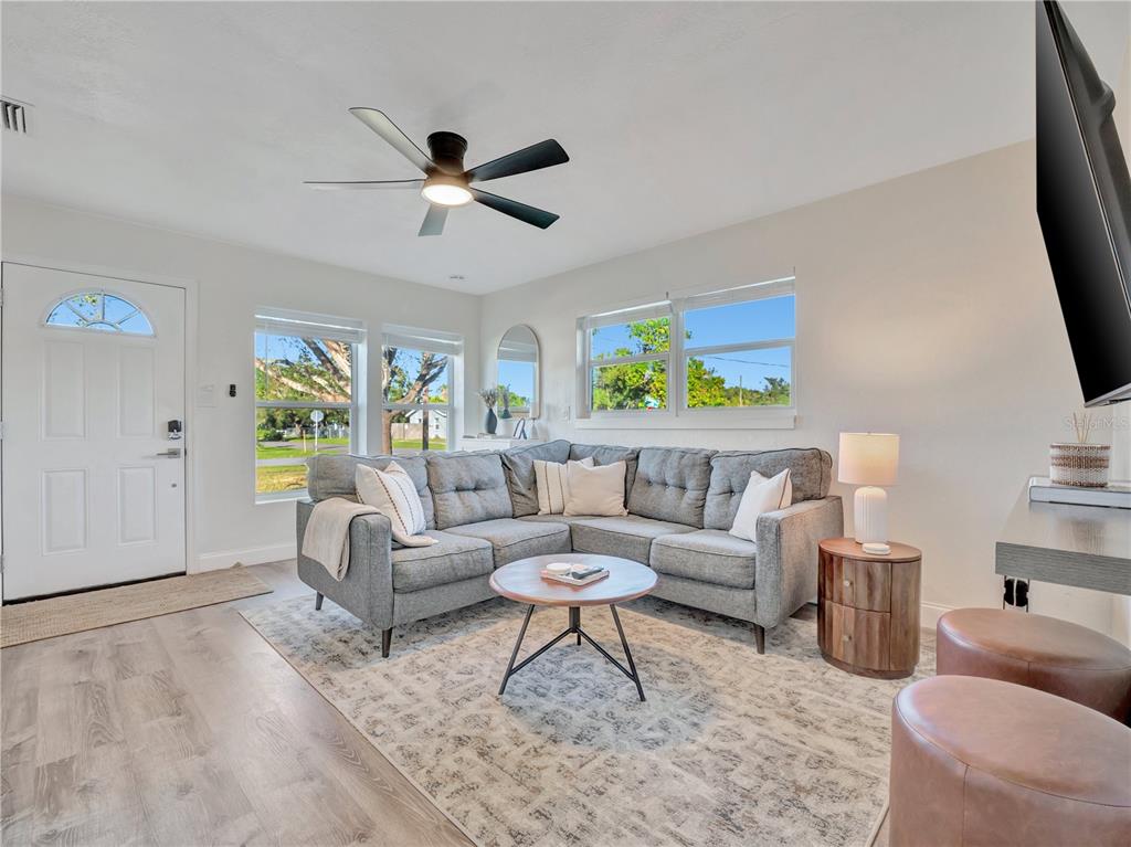 A living room features a gray sectional sofa, a round coffee table, and wood flooring — 4002 W OKLAHOMA AVENUE, TAMPA, FL