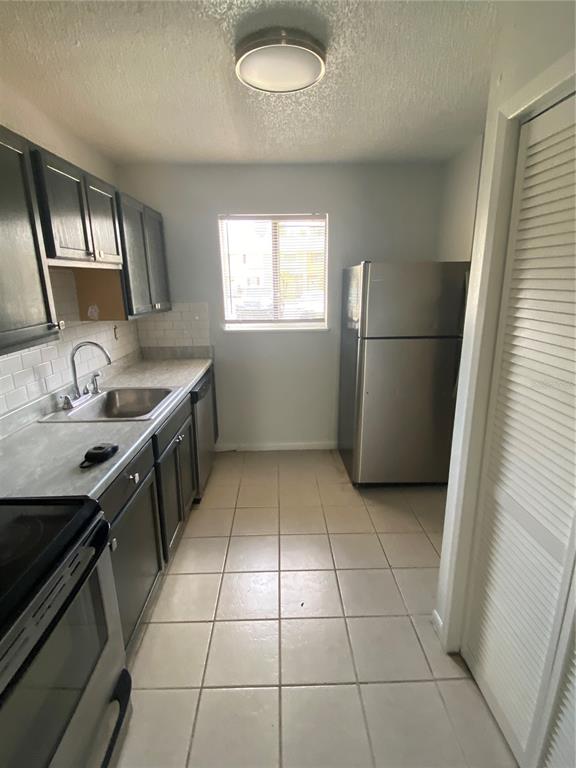 A kitchen features dark cabinets, stainless steel appliances, a tile floor, and a window — 22707 WATERSEDGE BOULEVARD UNIT 57, LAND O LAKES, FL