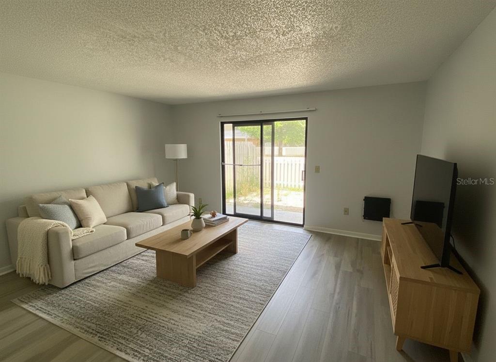 A living room features a beige sofa, wooden coffee table, television, and sliding glass doors — 22707 WATERSEDGE BOULEVARD UNIT 57, LAND O LAKES, FL