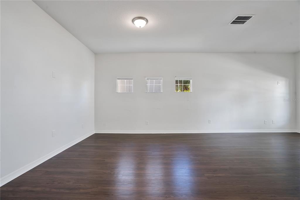 An empty room features white walls, dark wood-look flooring, and three small square windows — 432 YORK DALE DRIVE, RUSKIN, FL