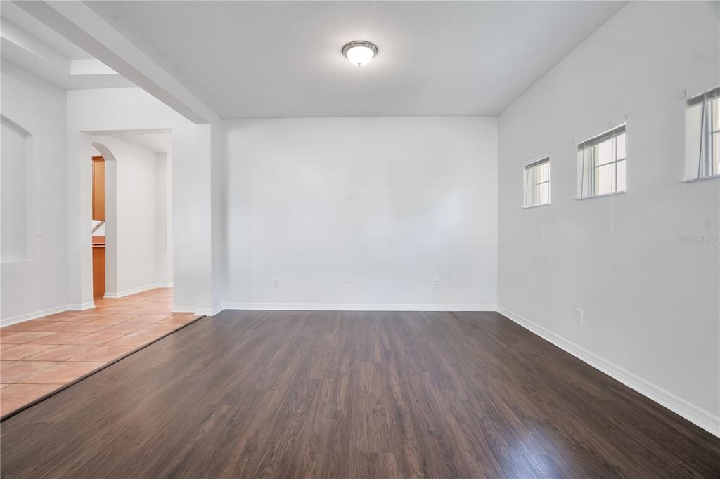 An empty room with dark wood-look flooring, white walls, and two small windows — 432 YORK DALE DRIVE, RUSKIN, FL