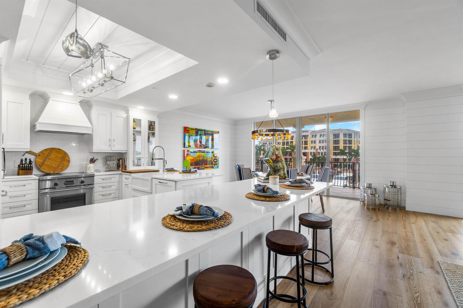 A bright kitchen features a large white island, wooden stools, and a view of buildings — 340 S Us Hwy 1 # 301, Jupiter FL 33477, JUPITER, FL