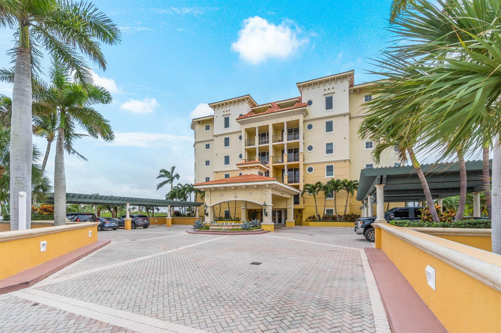 The exterior of a multi-story yellow building features a covered entrance and a paved driveway — 340 S Us Hwy 1 # 301, Jupiter FL 33477, JUPITER, FL
