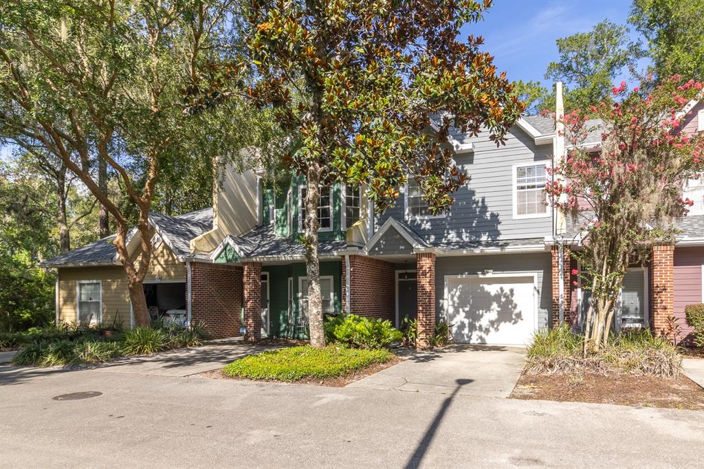 A multi-story townhouse complex with gray and tan siding, brick accents, and attached garages — 5047 NW 1ST PLACE UNIT 92, GAINESVILLE, FL