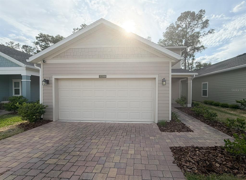 A beige house features a two-car garage, a paved driveway, and a stone walkway — 2258 NW 89TH WAY, GAINESVILLE, FL