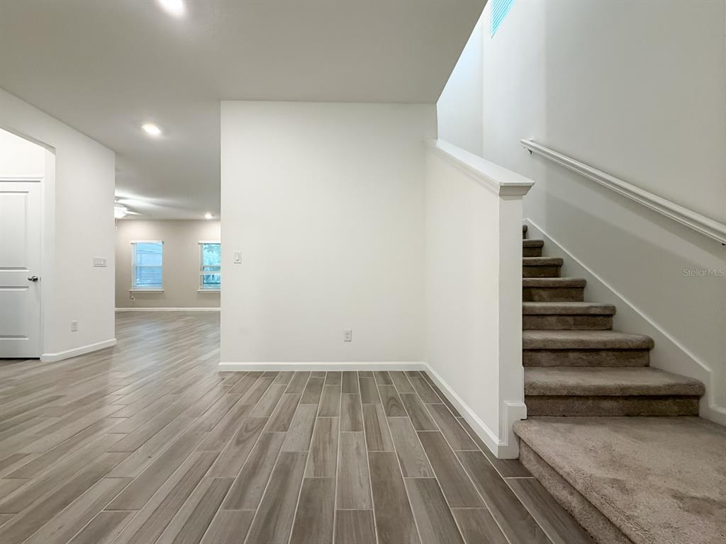A view of a home interior featuring wood-look tile flooring, a staircase, and white walls — 2258 NW 89TH WAY, GAINESVILLE, FL